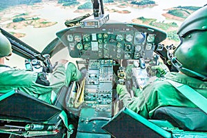 Military helicopter cockpit with two pilots flying over a tropical lake