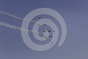 Military jets flying away in formation with white smoke trails