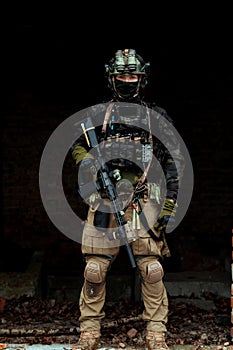 Military man in black uniform with machinegun. Soldier stand in the broken building. Vertical photo