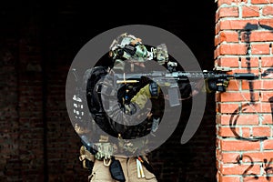 Military man in black uniformaims aims at the sight machinegun. Soldier in the broken building photo