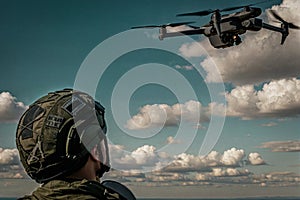 a military man looks at a drone close-up against the background of clouds