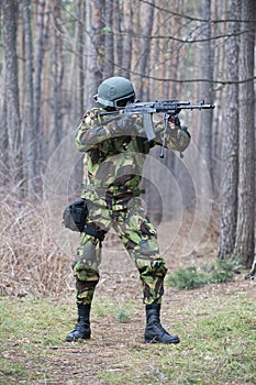 Military man shooting a rifle in the forest