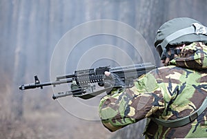 Military man shooting a rifle in the forest