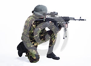 A military man sits on one knee and shoots a rifle. isolated