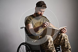 Military man sitting in a wheelchair and watching photos in an album