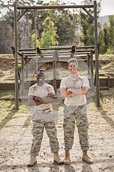 Military man standing with arms crossed during obstacle course in boot camp