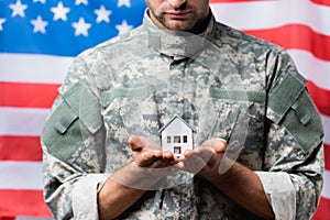 Military man in uniform holding house