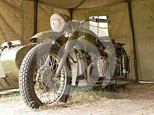 A military motorcycle with a sidecar under an awning. Military camouflage motor vehicles of the Second World War.