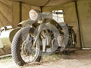 A military motorcycle with a sidecar under an awning. Military camouflage motor vehicles of the Second World War.