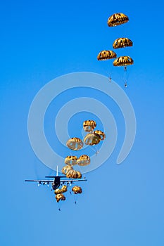 Military parachutist paratroopers parachute jumping out of a air force planes on a clear blue sky day photo