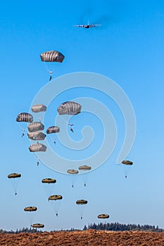 Military parachutist paratroopers parachute jumping out of a air force planes on a clear blue sky day photo