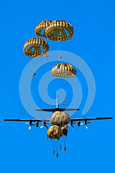 Military parachutist paratroopers parachute jumping out of a air force planes on a clear blue sky day photo