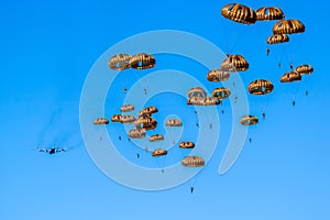 Military parachutist paratroopers parachute jumping out of a air force planes on a clear blue sky day photo