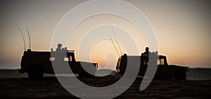 Military patrol car on sunset background. Army war concept. Silhouette of armored vehicle with soldiers ready to attack. Artwork