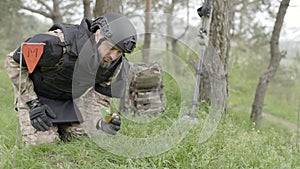 Military sapper demining an anti-tank mine in the field near the forest