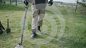 Military sapper with a metal detector in the field