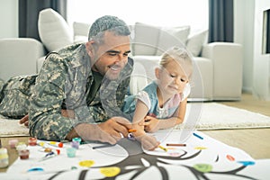 Military servant and his daughter painting family tree together