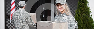 Military servicewoman holding cardboard box and