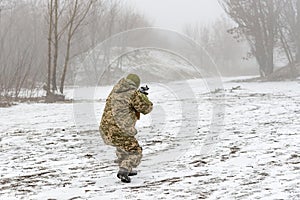 A military soldier in camouflage with a weapon goes on the offensive in winter