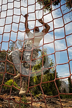 Military soldier climbing rope during obstacle course