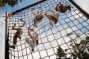 Military soldiers climbing rope during obstacle course