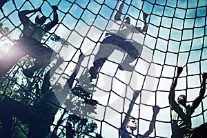 Military soldiers climbing rope during obstacle course photo