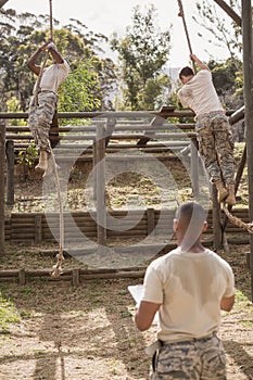 Military soldiers climbing rope during obstacle course training