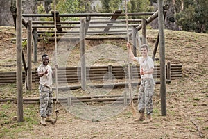 Military soldiers showing thumbs while holding rope during boot camp training