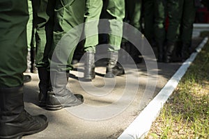 Military stands in row. Soldiers` shoes. Boots and military uniforms