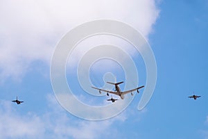 Military tanker aircraft refueler and fighter jets fly on blue sky