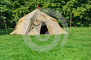 Military tent in the open meadow. Against the background of trees. The concept of military training, scout movement, outdoor