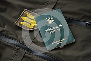 Military token or army ID ticket lies on green ukrainian military uniform