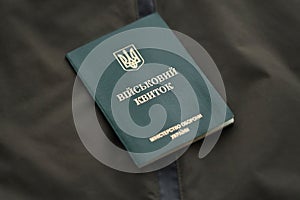 Military token or army ID ticket lies on green ukrainian military uniform