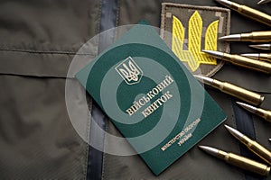 Military token or army ID ticket lies on green ukrainian military uniform