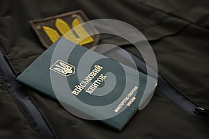 Military token or army ID ticket lies on green ukrainian military uniform