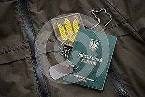 Military token or army ID ticket lies on green ukrainian military uniform