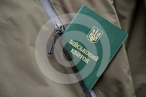 Military token or army ID ticket lies on green ukrainian military uniform