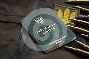 Military token or army ID ticket lies on green ukrainian military uniform