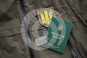 Military token or army ID ticket lies on green ukrainian military uniform