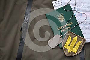 Military token or army ID ticket with mobilization notice lies on green ukrainian military uniform