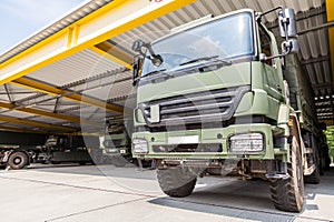 Military truck stands under military roof