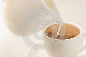 Milk is added to coffee cup/milk is added to coffee cup. Selective focus