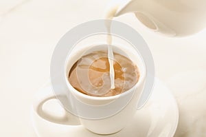 milk is added to coffee cup/milk is added to coffee cup on a white background. Selective focus