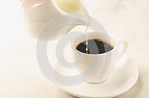 Milk is added to coffee white cup/milk is added to coffee cup on