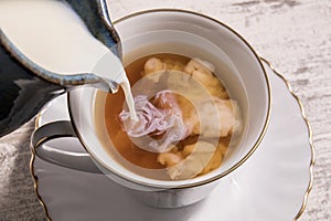 Milk being poured into a cup of hot tea