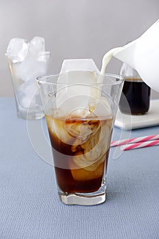 Milk being poured into a glass with cold brew coffee