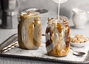 Milk Being Poured Into a Glass of Iced Coffee photo