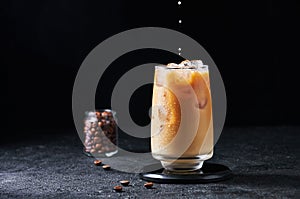 Milk Being Poured into Iced Coffee in Tall Glass on Dark Background. Concept Refreshing Summer Drink