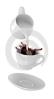 Milk being poured into small cup of coffee. Isolated white background