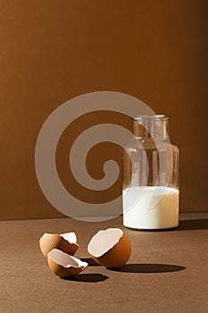 Milk in a bottle with eggs shells on brown background